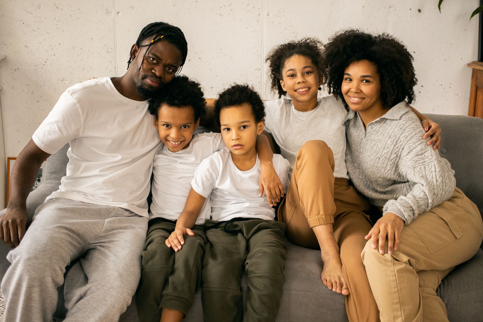 Two parents and their three children sitting together on a sofa.