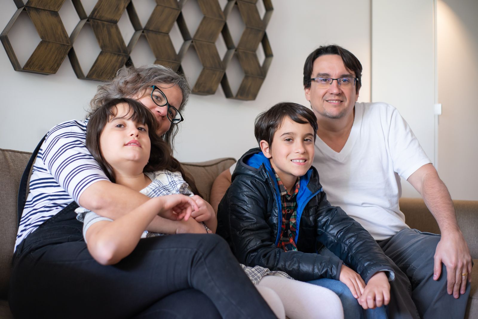 Two parents cuddling with their two children at home.